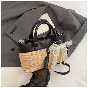 Detail of straw woven tote with black leather handle, lace bow and pearl chain charm