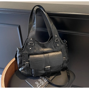 Detail of black vintage faux leather handbag with pleated texture and silver hardware rivets