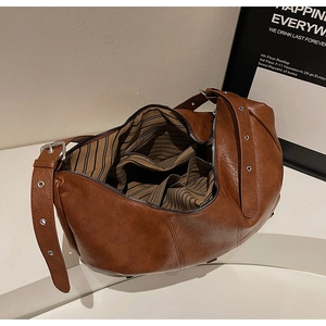Close-up of vintage brown leather tote with striped lining and silver eyelet strap detail