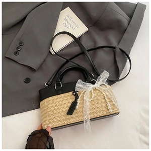 Detail of straw woven bag with black leather trim, white lace bow, and pearl chain strap