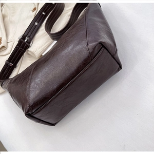 Close-up of vintage dark brown faux leather shoulder bag with glossy finish and silver buckle