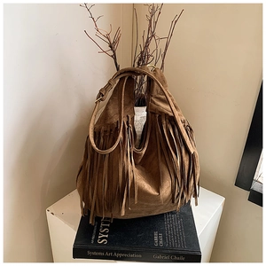 Artistic close-up of brown suede hobo bag with long fringes and adjustable leather strap