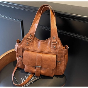 Detail view of brown vintage leather handbag with decorative metal buckles and rivets