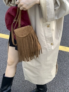Sac bandoulière vintage en daim marron avec franges présenté dans un style urbain