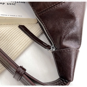 Detailed close-up of dark brown vintage dumpling bag with glossy leather texture and zipper