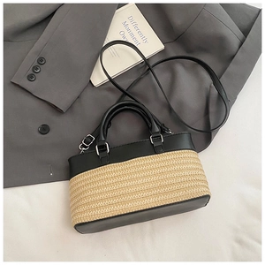 Detail of woven straw and black leather handbag with silver metal buckles on a blazer