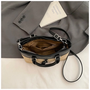 Close-up of woven straw tote with black leather trim showing internal zipper pocket