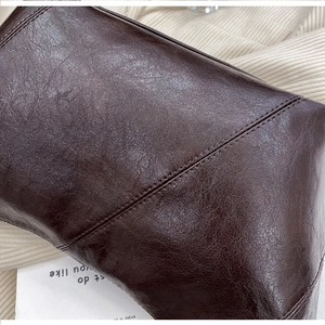 Close-up of dark brown oil-wax leather texture with reinforced double-stitch details