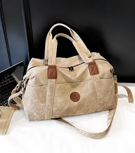 Dettaglio borsa da viaggio in tela kaki con finiture in pelle marrone e tasca esterna