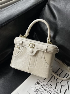 Vintage beige denim-style square box bag with gold hardware on a leather stand