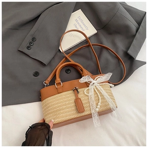 Detail of woven straw tote bag with brown faux leather trim and lace pearl bow charm