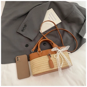 Detail of straw woven tote with brown leather trim, white lace bow, and pearl charm