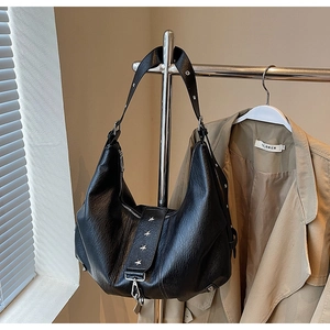 Detail of black lychee grain leather tote bag with silver star rivets on adjustable strap