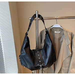 Detail of black faux leather tote with silver star rivets and adjustable shoulder strap
