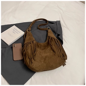 Detailed view of dark brown suede hobo bag featuring retro fringe and vintage gold hardware