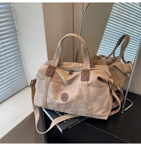 Dettaglio della borsa da viaggio kaki con logo JM e manici in pelle rinforzati