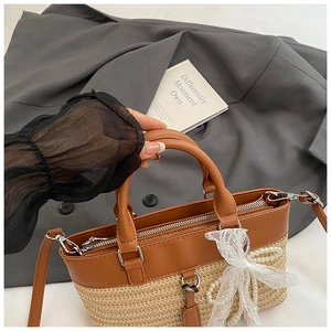 Detail of straw patchwork handbag with leather trim and pearl lace bow accessory
