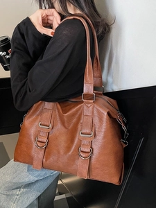 Large brown faux leather tote bag with metallic buckles shown on model for daily use