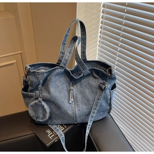 Detail of blue denim tote bag with side drawstring pocket and detachable round coin purse