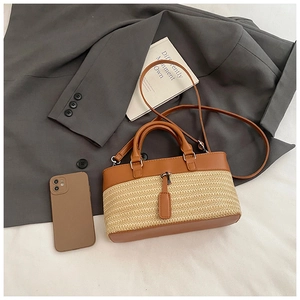 Close-up of contrast woven straw tote featuring brown leather handles and shoulder strap