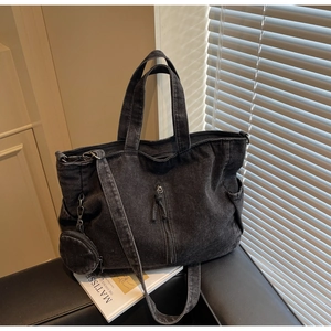 Detail of black washed denim tote bag with textured surface and functional zippers