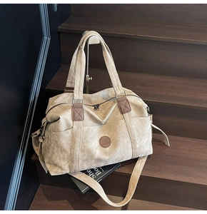 Dettaglio borsa da viaggio in tela kaki con finiture in pelle marrone e tracolla rimovibile