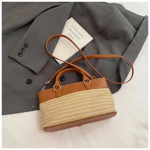 Flat lay of straw tote bag with brown leather details and silver hardware on a blazer