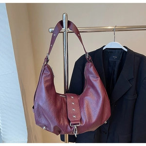 Detail of burgundy lychee leather tote with silver star studs on the shoulder strap