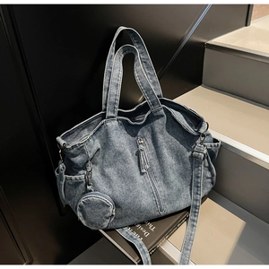 Detail of blue denim tote bag with vertical zipper tassel and round mini coin purse charm