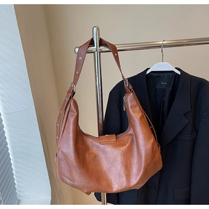 Brown leather tote with adjustable eyelet shoulder strap and metallic buckle detail