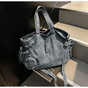 Detail view of denim tote bag with adjustable strap and mini round coin purse pendant