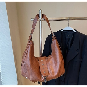 Detail of brown faux leather tote with silver star rivets and wide adjustable strap