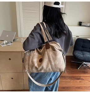 Dettaglio macro della borsa da viaggio in tela kaki con manici in pelle e toppa rotonda