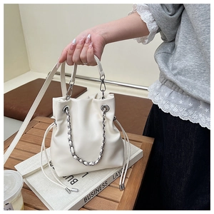 Close-up of white leather bucket bag with silver chunky chain and drawstring detail