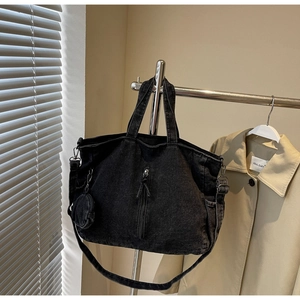 Detail of black washed denim tote bag with dual handles and detachable shoulder strap