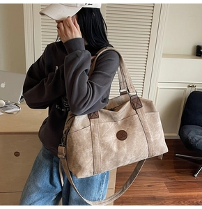 Vista dettagliata della borsa da viaggio in tela kaki con manici in pelle marrone
