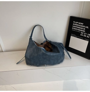 Detail of adjustable strap and silver metal buckle on soft matte leather tote bag