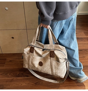 Dettaglio di una borsa da viaggio in tela kaki vintage con rifiniture in pelle marrone