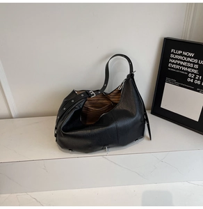 Detail of black pebbled leather tote showing the wide adjustable strap and metal eyelets