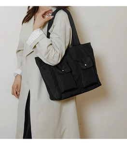 Macro shot of large capacity black nylon tote bag featuring dual front pockets and metal snaps