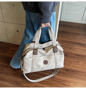 Grande borsa da viaggio in tela beige con dettagli in pelle marrone e fibbie metalliche