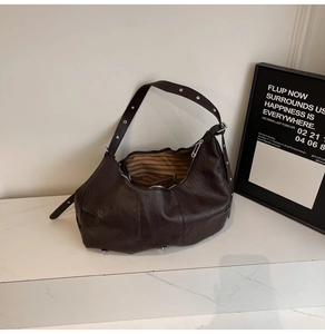 Detail of soft dark brown leather tote bag with silver eyelets on a wide shoulder strap