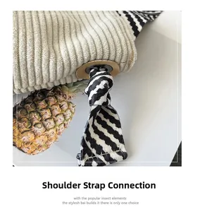 Detail of beige corduroy tote with zebra print strap and silver metal eyelet connector