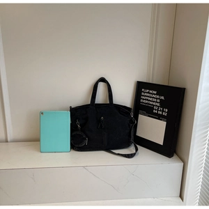 Detail of black denim tote bag showing large capacity with tablet for size reference