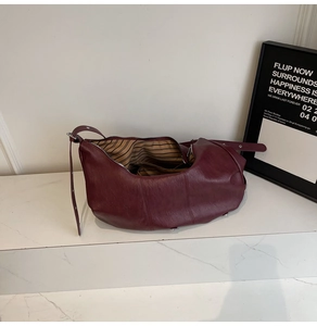 Detail view of burgundy leather tote bag showing striped lining and crescent shape design