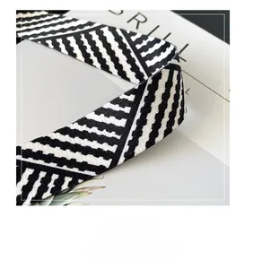 Close-up of wide fabric shoulder strap featuring black and white geometric zigzag patterns