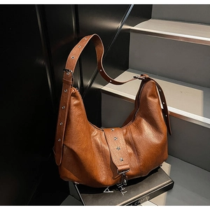 Detailed view of brown faux leather hobo bag with star rivets on industrial stairs