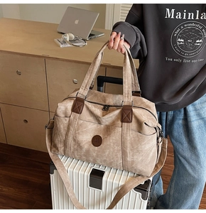 Dettaglio della borsa da viaggio in tela kaki con logo in pelle su una valigia