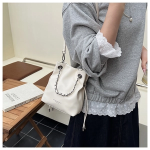 Close-up of beige drawstring bucket bag with silver metal chain and logo detail