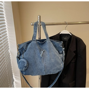 Detail of blue denim tote bag featuring long strap and a round coin purse charm